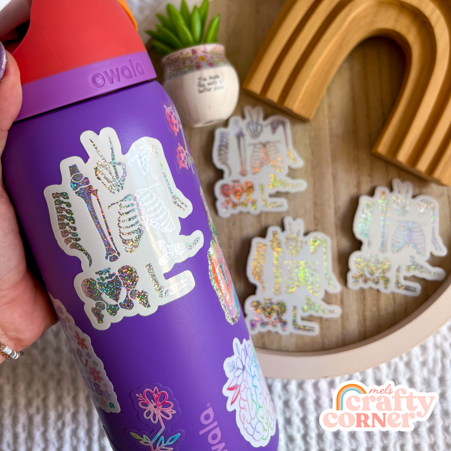 Hand holding Skeleton Boneyard holographic sticker showing size and scale by Mel's Crafty Corner