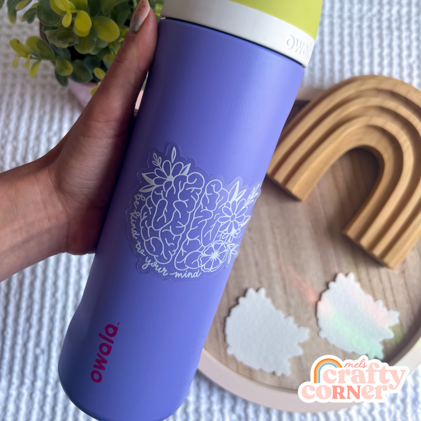 Flat lay of Be Kind to Your Mind clear sticker showing transparency
