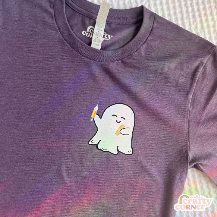 Flat lay view of purple Boo-Boo Ghostie softest t-shirt by Mel's Crafty Corner