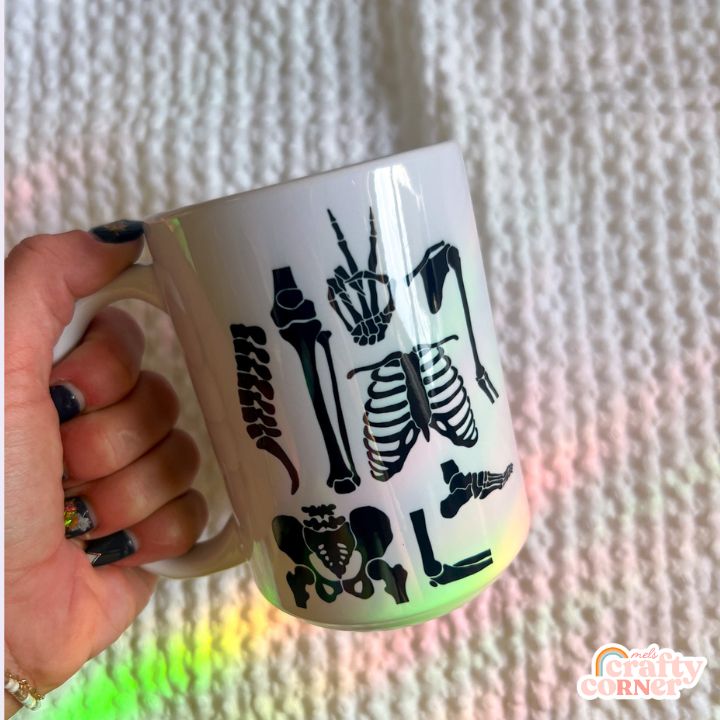 Hand holding Skeleton Boneyard 15 oz ceramic mug showing size and scale by Mel's Crafty Corner